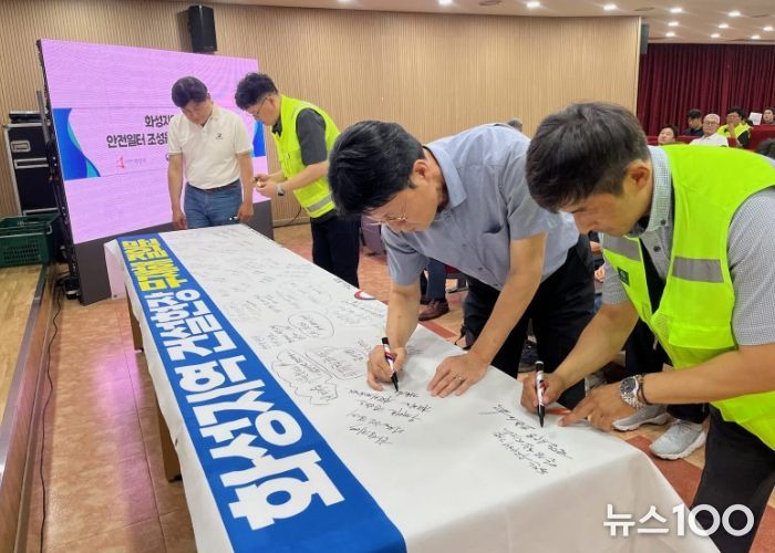 화성특례시 관내 공사현장 관계자 및 안전관리자들이 30일 무재해 결의대회에서 무재해 결의문 현수막에 안전기원 문구를 적고 있다.